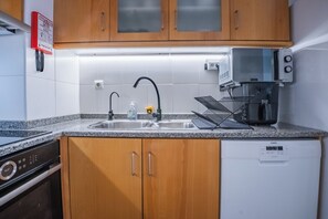 Une cuisine dotée d’armoires en bois, d’un évier en acier inoxydable, d’un four à micro-ondes et d’un lave-vaisselle.