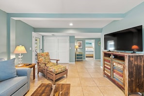 A living room with a sofa, armchair, television, and a wooden cabinet. - Welcome to Sisters By The Sea! (St. George Island)