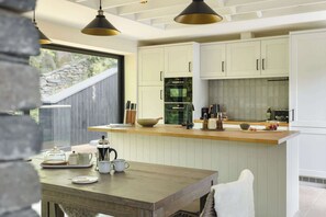 Une cuisine moderne avec des armoires blanches, un plan de travail en bois et une grande fenêtre.