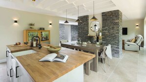 A modern kitchen with a wooden island, stone accent walls, and pendant lighting. - Fawns Keep - Hot Tub & Sauna Retreat | Ridgestone (Bowness-on-Windermere)