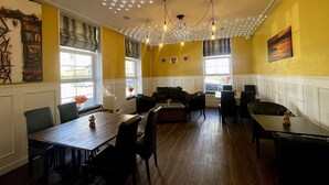 A dining area with a wooden table, chairs, a chandelier, and artwork on the walls.