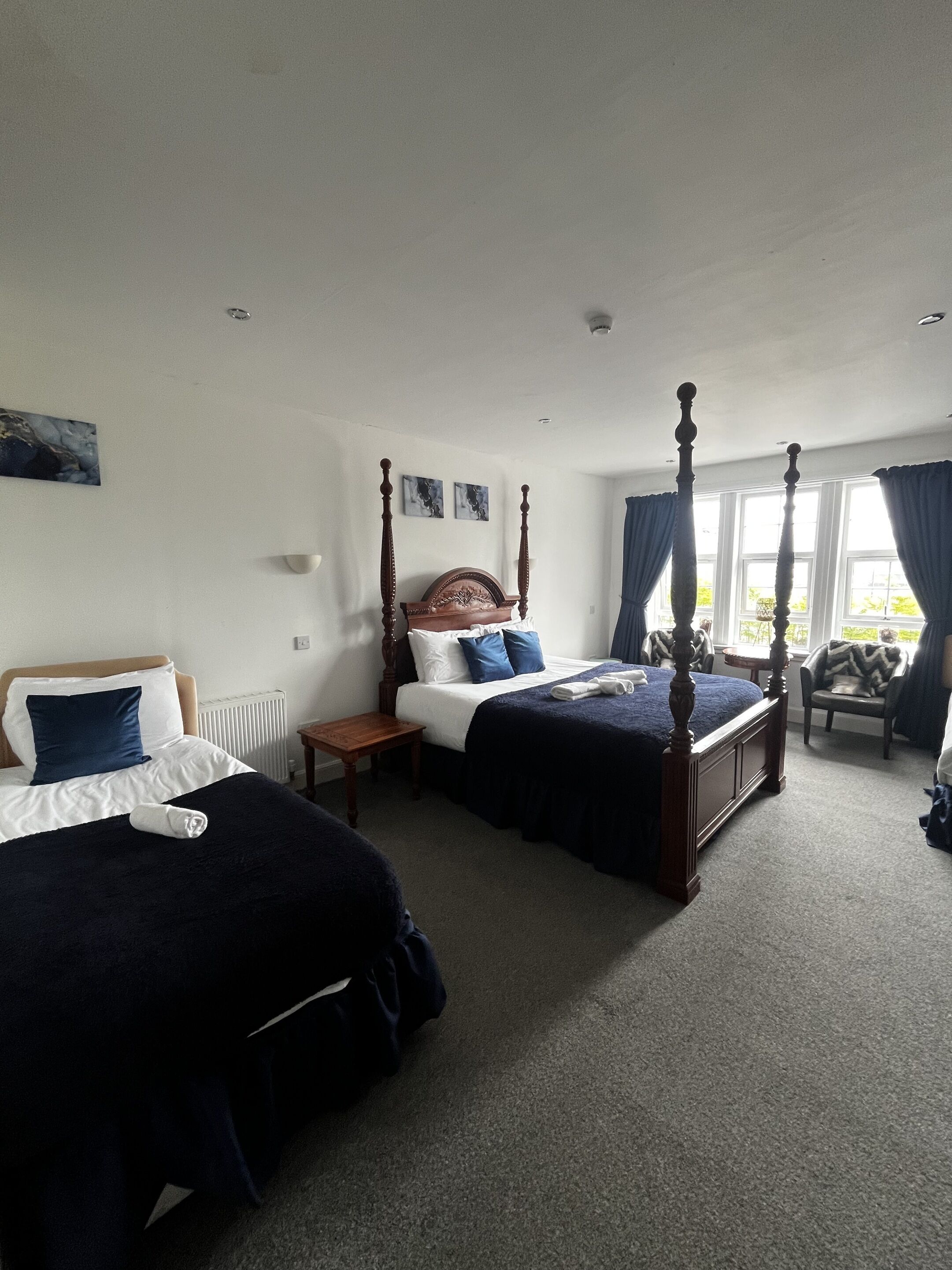 Een slaapkamer met twee bedden, een houten hemelbed, een stoel en een tafel.