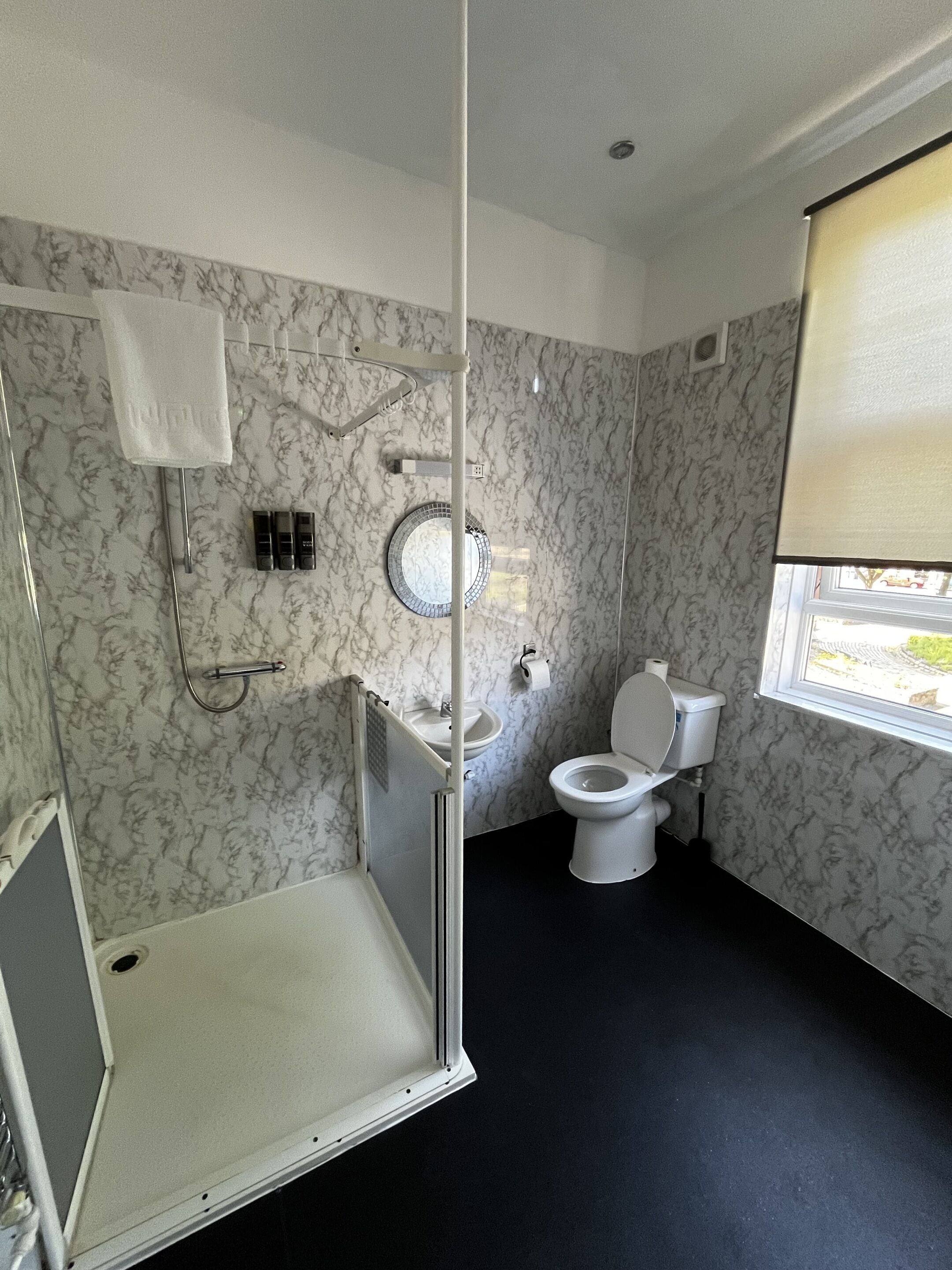 Un baño con ducha, inodoro, lavabo y ventana.