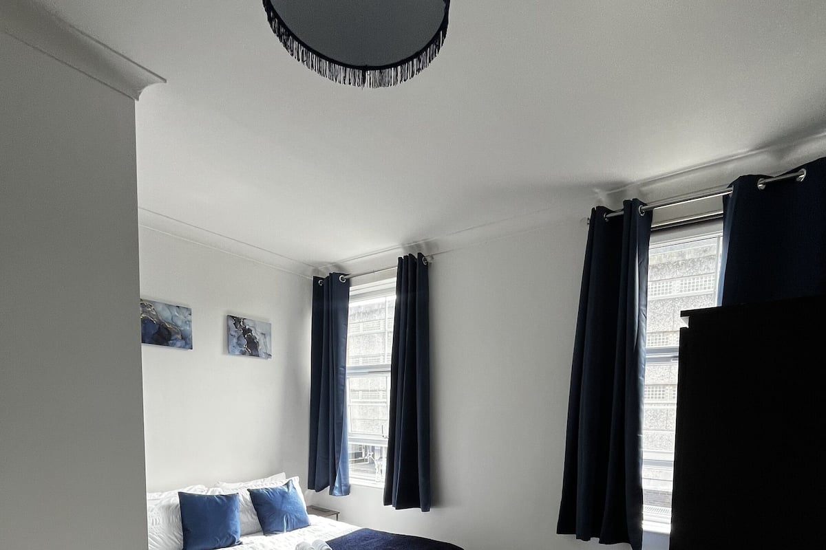Escritorio, cortinas blackout y tabla de planchar con plancha