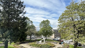 A parking lot with cars, a central sculpture, and surrounding trees.