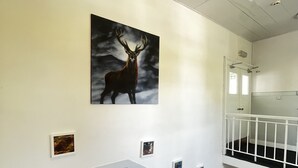 A staircase with a railing, a wall-mounted picture of a deer, and a white door with a window. - The Harbour Hotel (Greenock)
