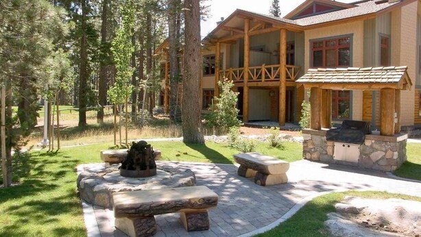 Eine Lodge mit Feuerstelle aus Stein, Sitzgelegenheiten im Freien und Grillbereich aus Stein.