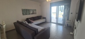 A living room with a sofa, a small table, and a TV. There is a sliding glass door leading outside. - Groundfloor, oasis beach 2 la zenia (La Zenia)