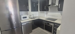 A compact kitchen with a stainless steel refrigerator, a microwave, a dishwasher, a sink, and a stove. - Groundfloor, oasis beach 2 la zenia (La Zenia)