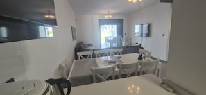 A modern kitchen with a dining area, a TV mounted on the wall, and a sliding glass door leading to an outdoor area. - Groundfloor, oasis beach 2 la zenia (La Zenia)