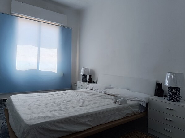 Ein Schlafzimmer mit Bett, Nachttische, einem Fenster und einem Beistelltisch.