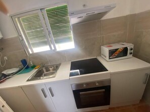 Una cuina amb microones integrat, un rentaplat i una cuina.