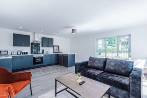 A modern living space with a kitchen, a sofa, and a coffee table. - Stylish 2BDR Hospitals Nearby Free Parking (Liverpool)