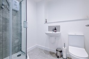 Ein modernes Badezimmer mit einer Duschkabine aus Glas, einem weißen Waschbecken und einer Toilette.