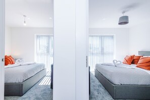 Ein modernes Schlafzimmer mit einem Bett, Kissen, einem Nachttisch und einem Fenster mit Jalousien.