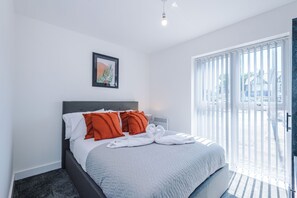 Una habitación de hotel con una cama, un cuadro en la pared y vistas al exterior por la ventana.
