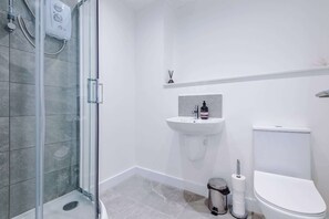 A bathroom with a glass shower enclosure, a white sink, and a toilet. - Stylish 2BDR Hospitals Nearby Free Parking (Liverpool)