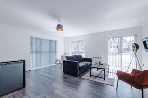 A modern living room with a sofa, a coffee table, and a dining area. - Stylish 2BDR Hospitals Nearby Free Parking (Liverpool)