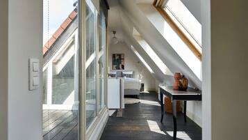 Een kamer met hoge plafonds, dakramen, een bed, een bureau en een stoel.