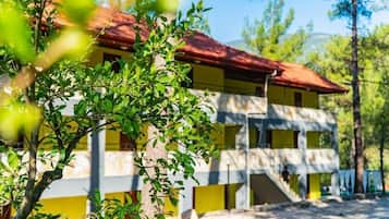 Un edificio de dos pisos con techo rojo, rodeado de vegetación.