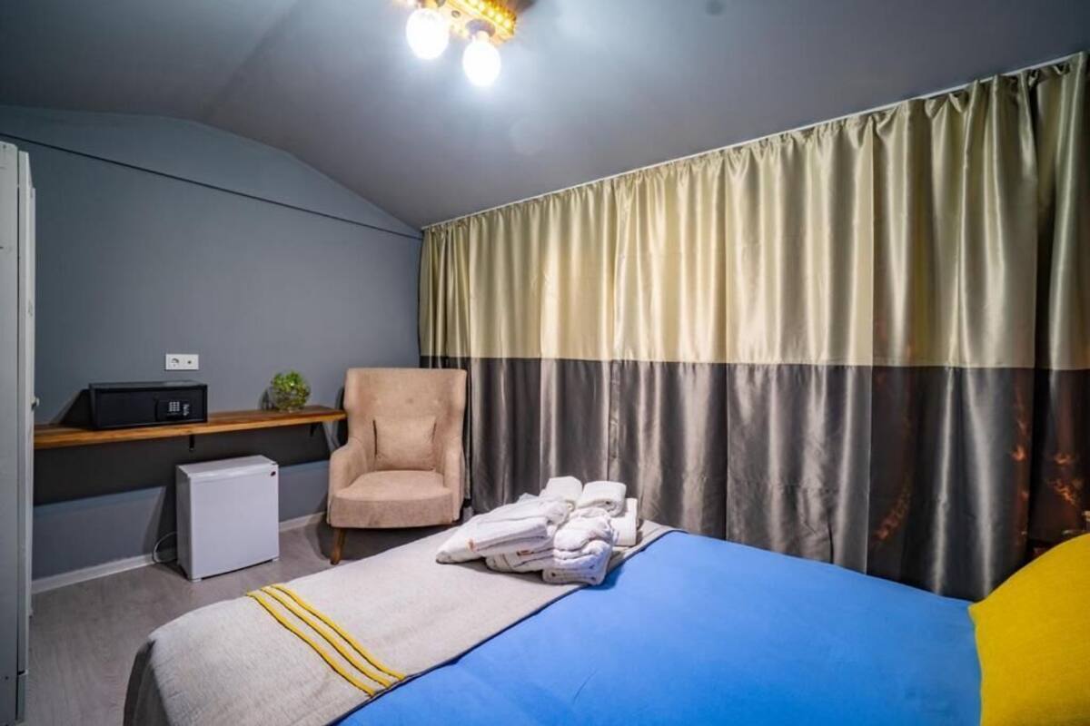 Ein Hotelzimmer mit einem Bett, einem Sessel, einem Schreibtisch mit Computer und einem kleinen Kühlschrank.
