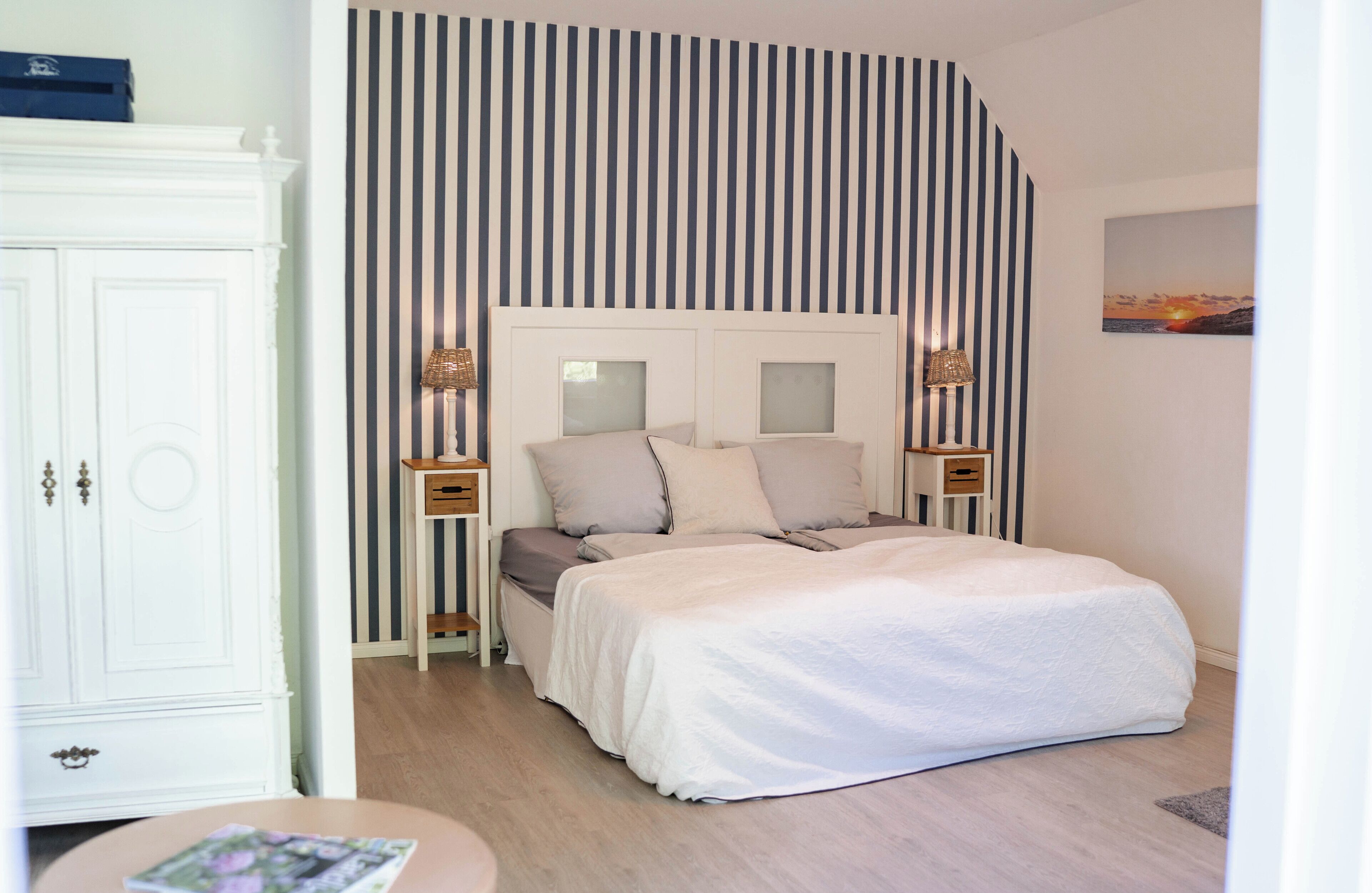 A bedroom with a bed, bedside tables, a wardrobe, and a striped wall.