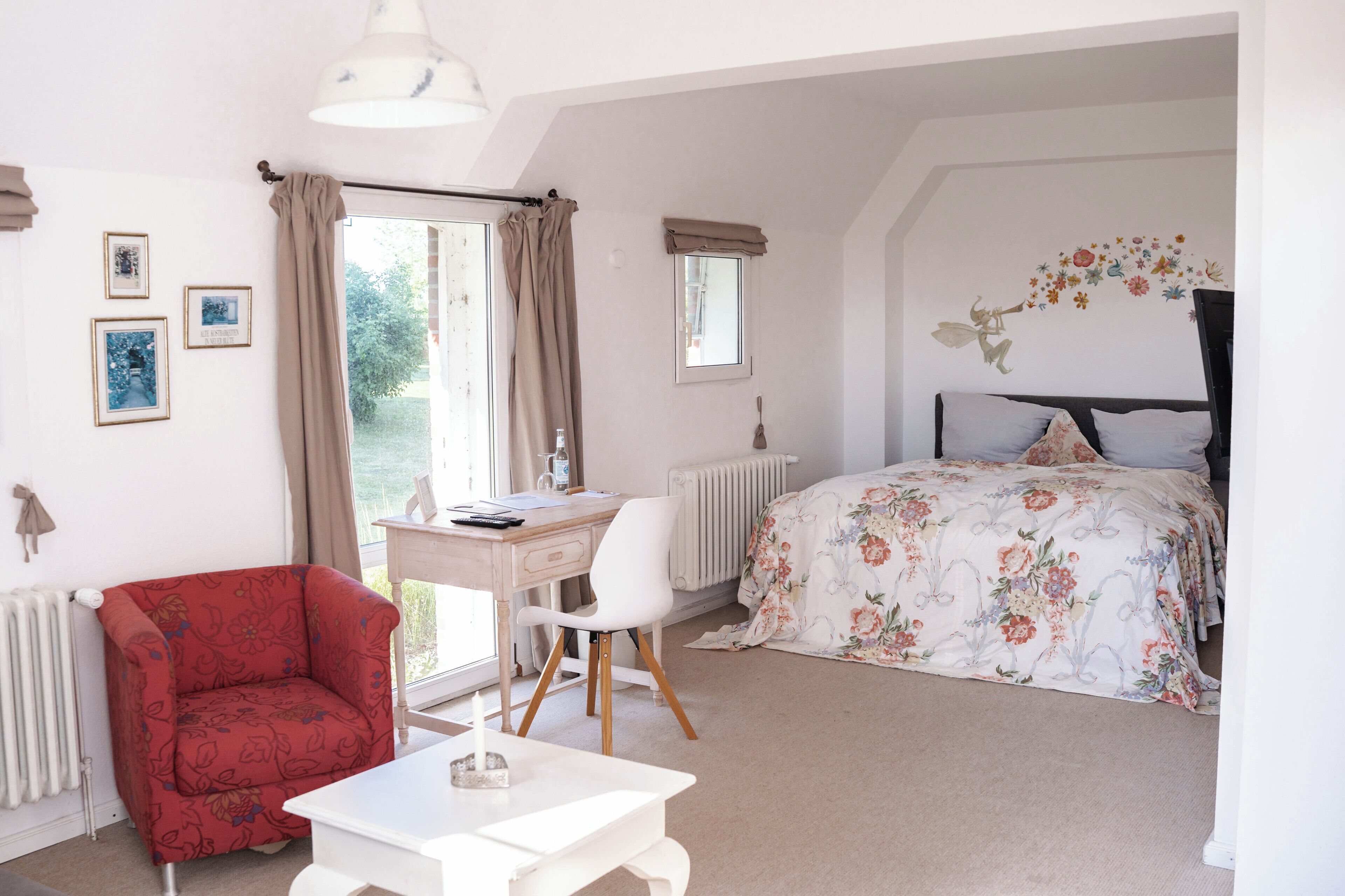 A bedroom with a bed, a desk, a chair, a radiator, and a window with curtains.