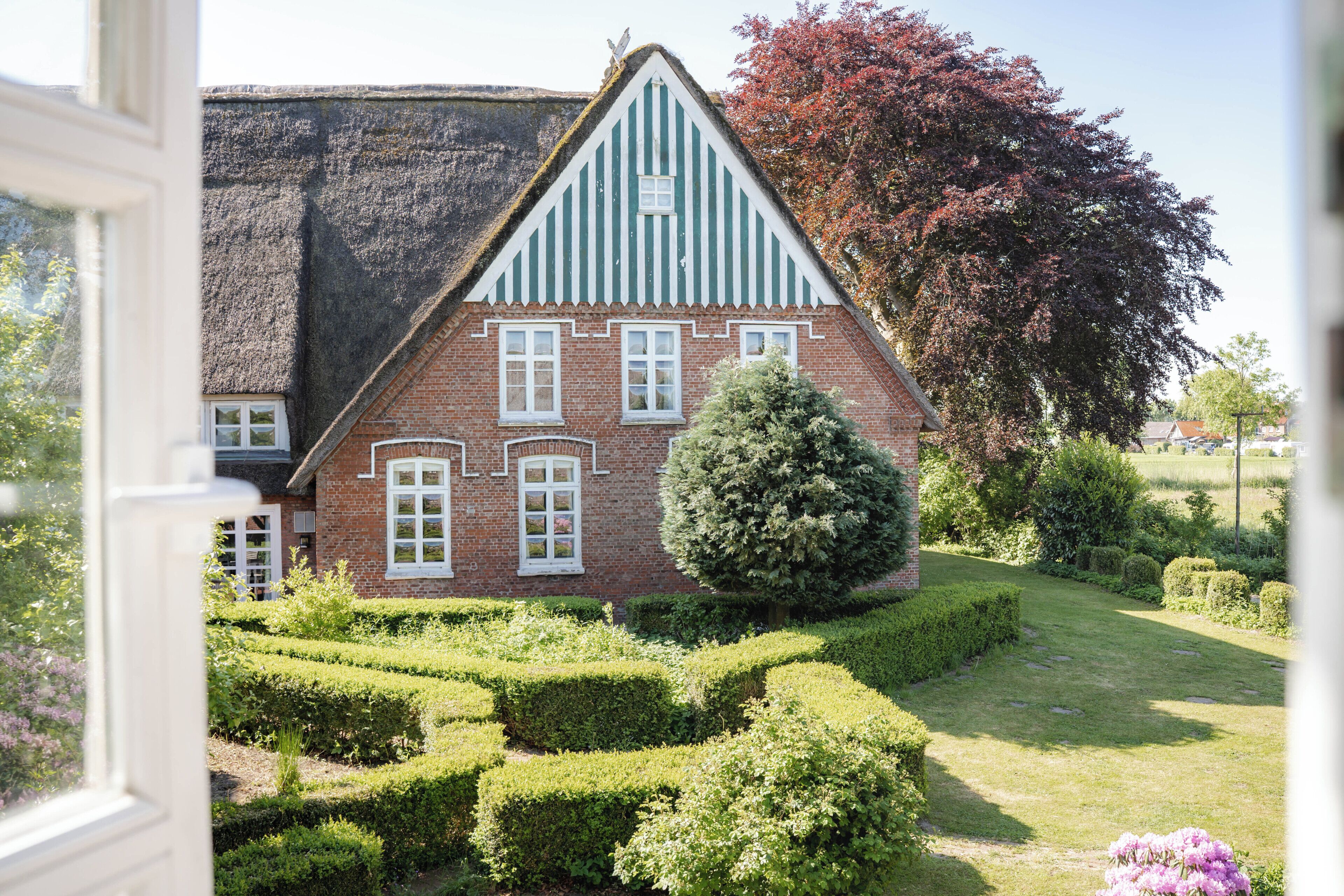 Ein traditionelles Haus mit steilem Satteldach, einer Ziegel-Fassade und Fenstern mit weißen Rahmen.