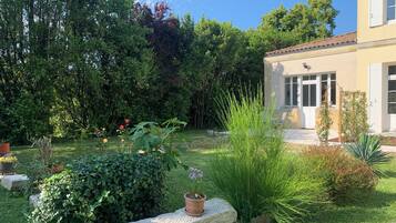 A garden with a stone bench, potted plants, and a building with a tiled roof.