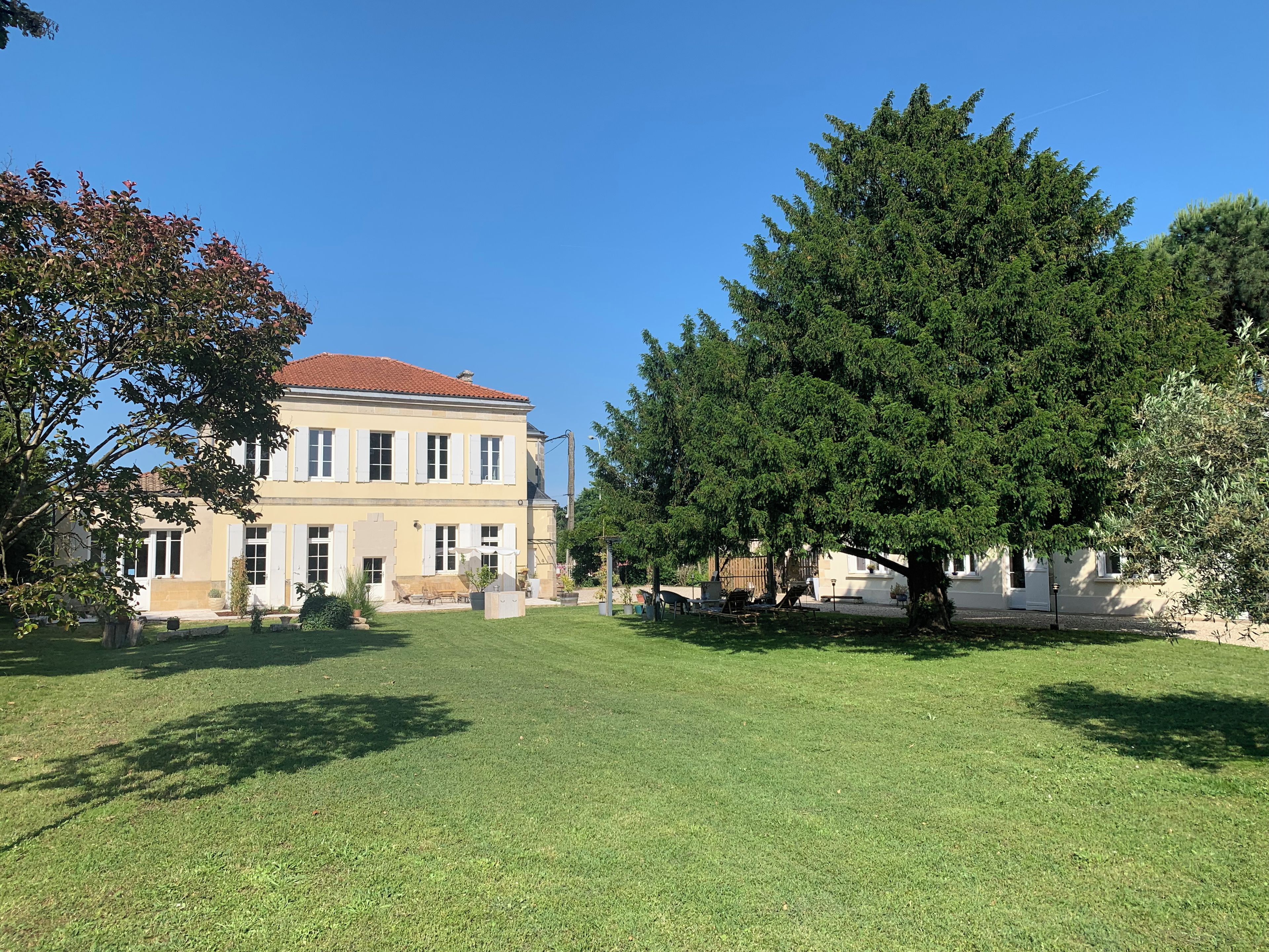 A two-story building with a red-tiled roof, surrounded by a well-maintained lawn and large trees.