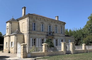 A large, historic building with a symmetrical facade, multiple windows, and a gated entrance.