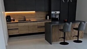 A modern kitchen with a central island, bar stools, and a built-in oven. - Seaview 8 Bed Villa Sleeps 16 - Pool & Hot tub (Starigrad)
