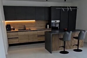 A modern kitchen with a central island, bar stools, and a built-in oven. - Seaview 8 Bed Villa Sleeps 16 - Pool & Hot tub (Starigrad)