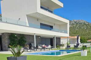 A modern two-story house with a swimming pool, outdoor seating, and a mountain backdrop. - Seaview 8 Bed Villa Sleeps 16 - Pool & Hot tub (Starigrad)