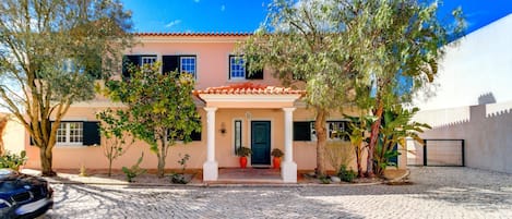 Une maison avec un toit en tuiles, un porche à l’avant et une allée pavée.