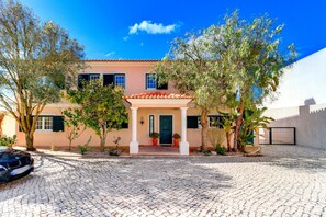 A house with a tiled roof, a front porch, and a cobblestone driveway. - Luxury Coastal Villa with Heated Pool,  Basketball Court & Ocean Views near Lisbon (Atalaia de Cima)