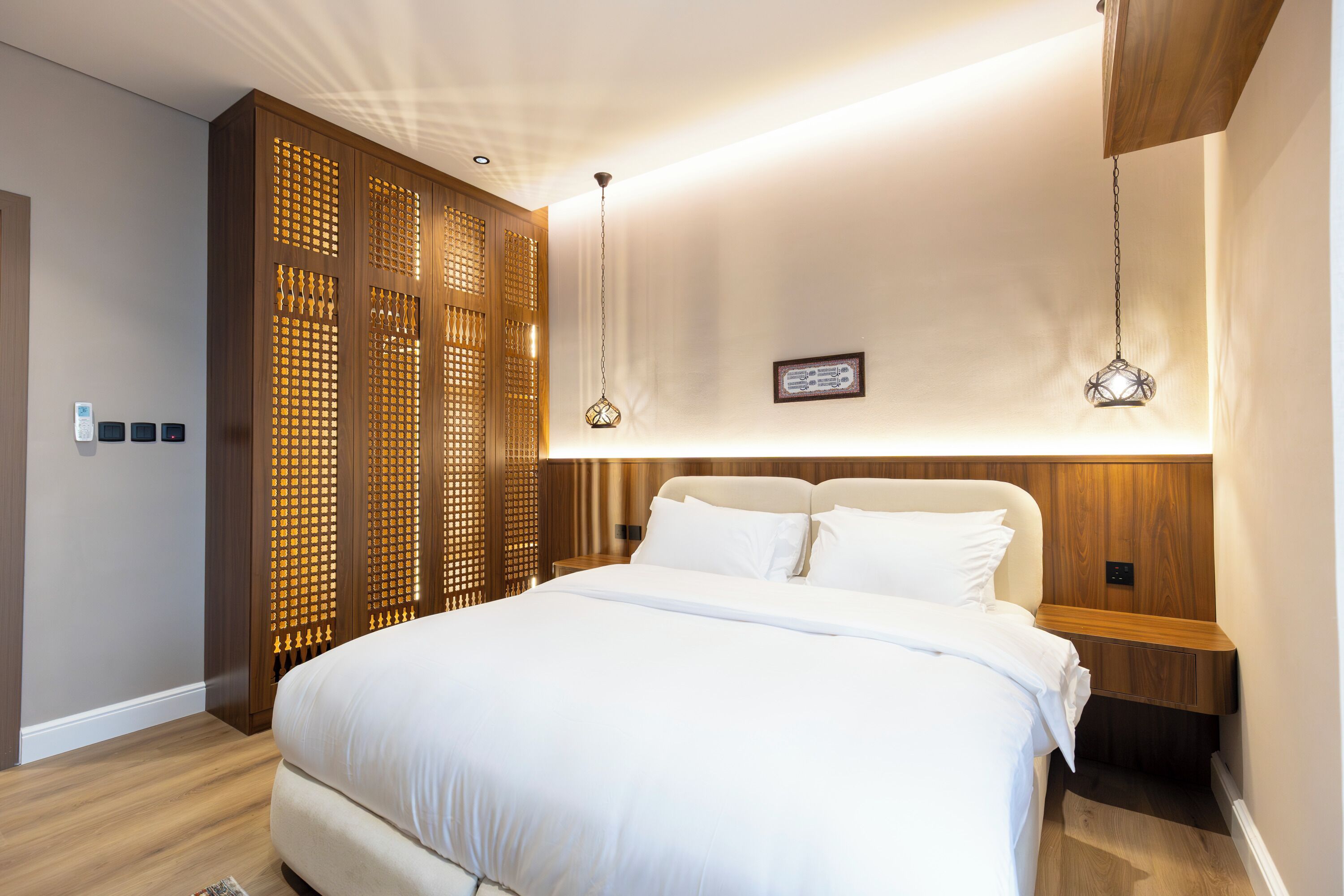 Une chambre moderne avec un grand lit, une tête de lit en bois et un panneau décoratif mural.
