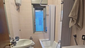 Un baño pequeño con lavamanos, inodoro, bañera y lavadora.