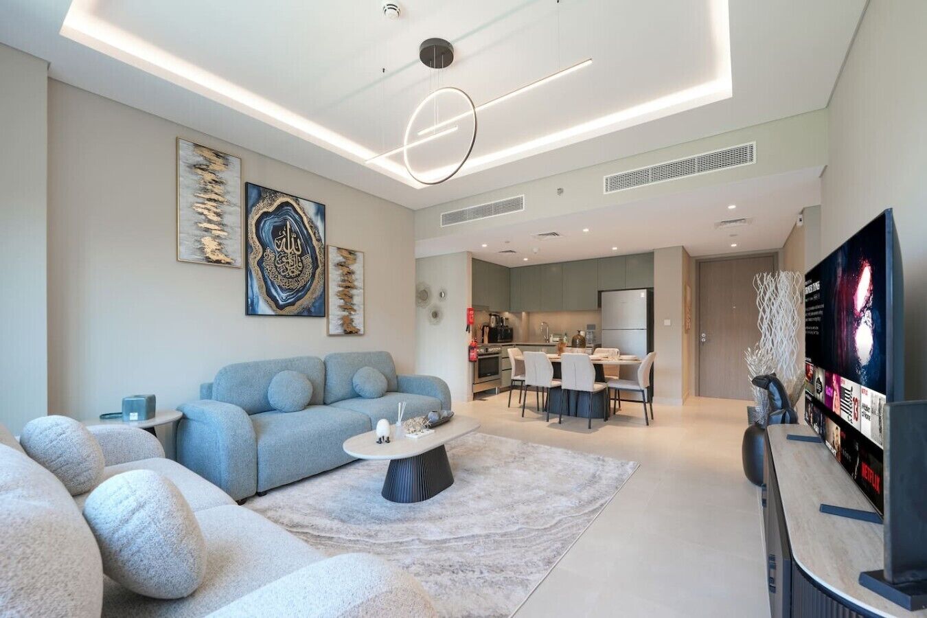 Un salon moderne avec un canapé, une table basse et un tél éviseur. Il y a également un coin cuisine avec une table à manger et des chaises.