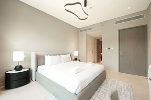 Ein modernes Hotelzimmer mit einem großen Bett, Nachttischen mit Lampen, einem Kleiderschrank und einem durchgegangenen Badezimmer.