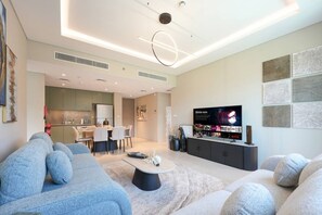 A modern living room with a sofa, coffee table, and a flat-screen TV. - Elegant 2BR Haven in Viridian by Central Park (Dubai)