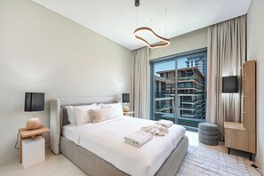 A modern hotel bedroom with a large bed, bedside tables, a TV, and a view of a building. - Elegant 2BR Haven in Viridian by Central Park (Dubai)