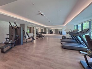 Ein modernes Fitnessstudio mit Laufbändern, Kraftgeräten und einer Spiegelwand.