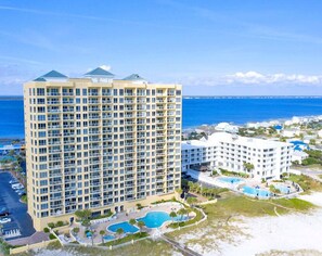 Ein Hochhaus-Hotel mit mehreren Balkonen, einem Schwimmbad und Blick auf den Strand.