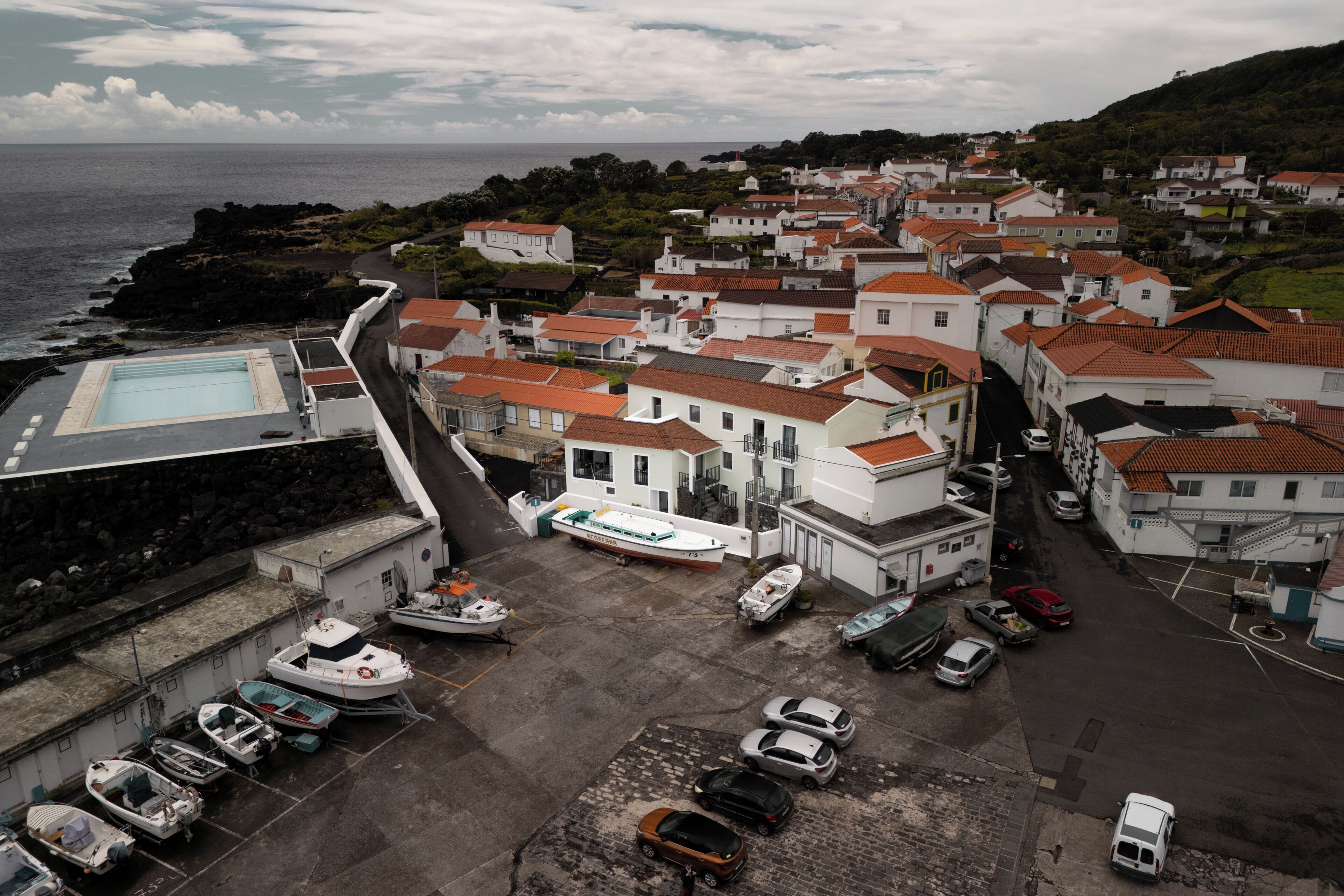 A coastal town with white buildings, a marina with boats, and a road leading to the sea.