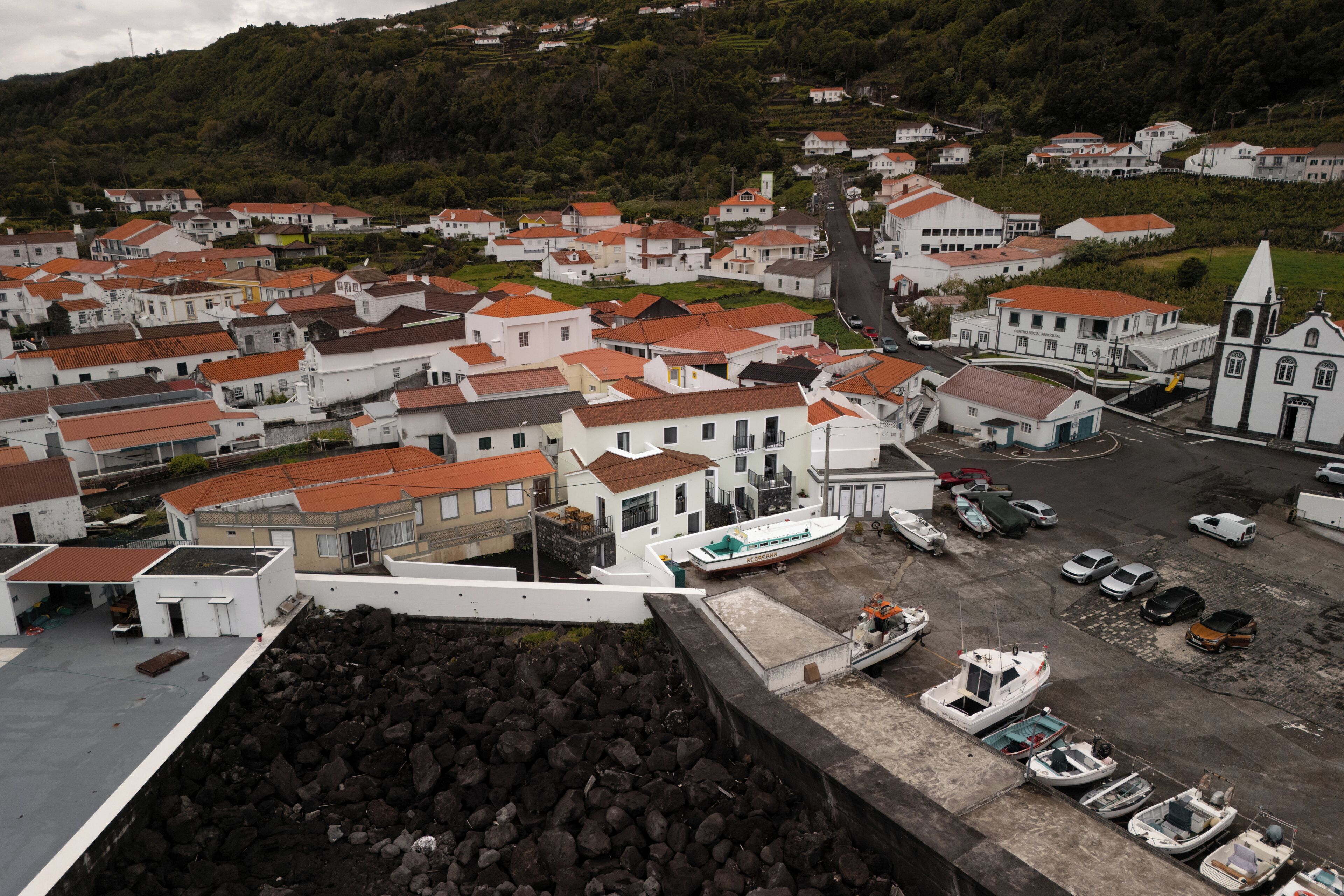 A coastal town with white buildings, a church, and boats docked at the harbor.