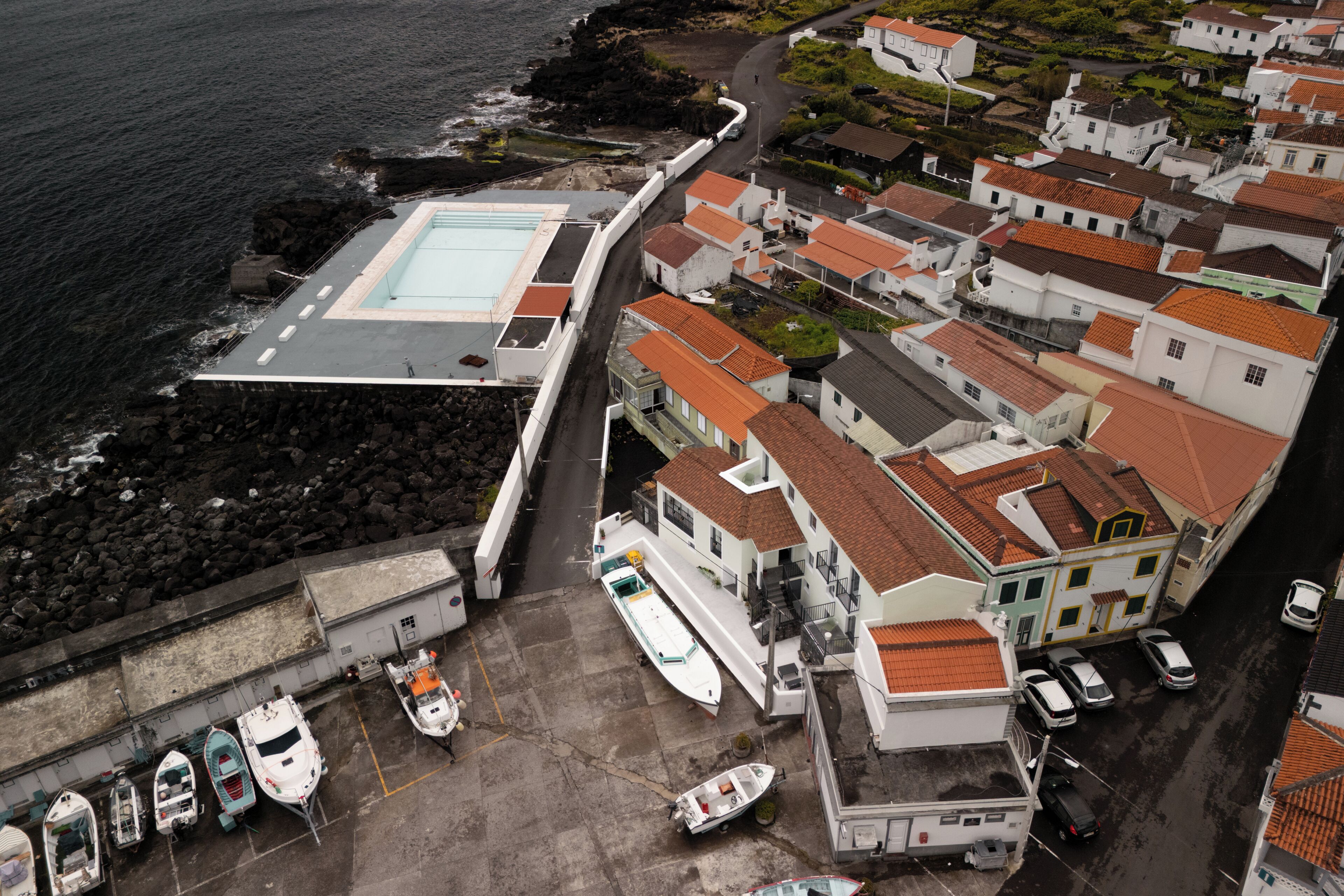 Un poble costaner amb un port esportiu, edificis blancs amb teulades vermelles i una piscina.
