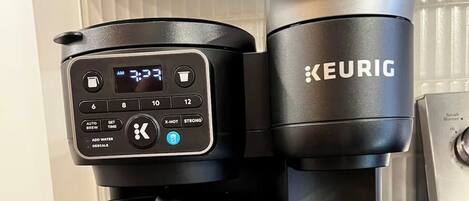 Una cafetera Keurig con pantalla digital, una jarra y un soporte para cápsulas sobre una encimera de cocina.