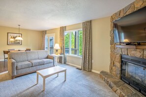 A living room with a stone fireplace, a sofa, a coffee table, and a television. - Eagle Trace Two Bedroom Condo (Mc Gaheysville)