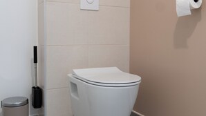 A modern bathroom with a toilet, a trash bin, and a toilet paper holder on the wall. - Studio Calypso 20 m from the sea (Mauguio)